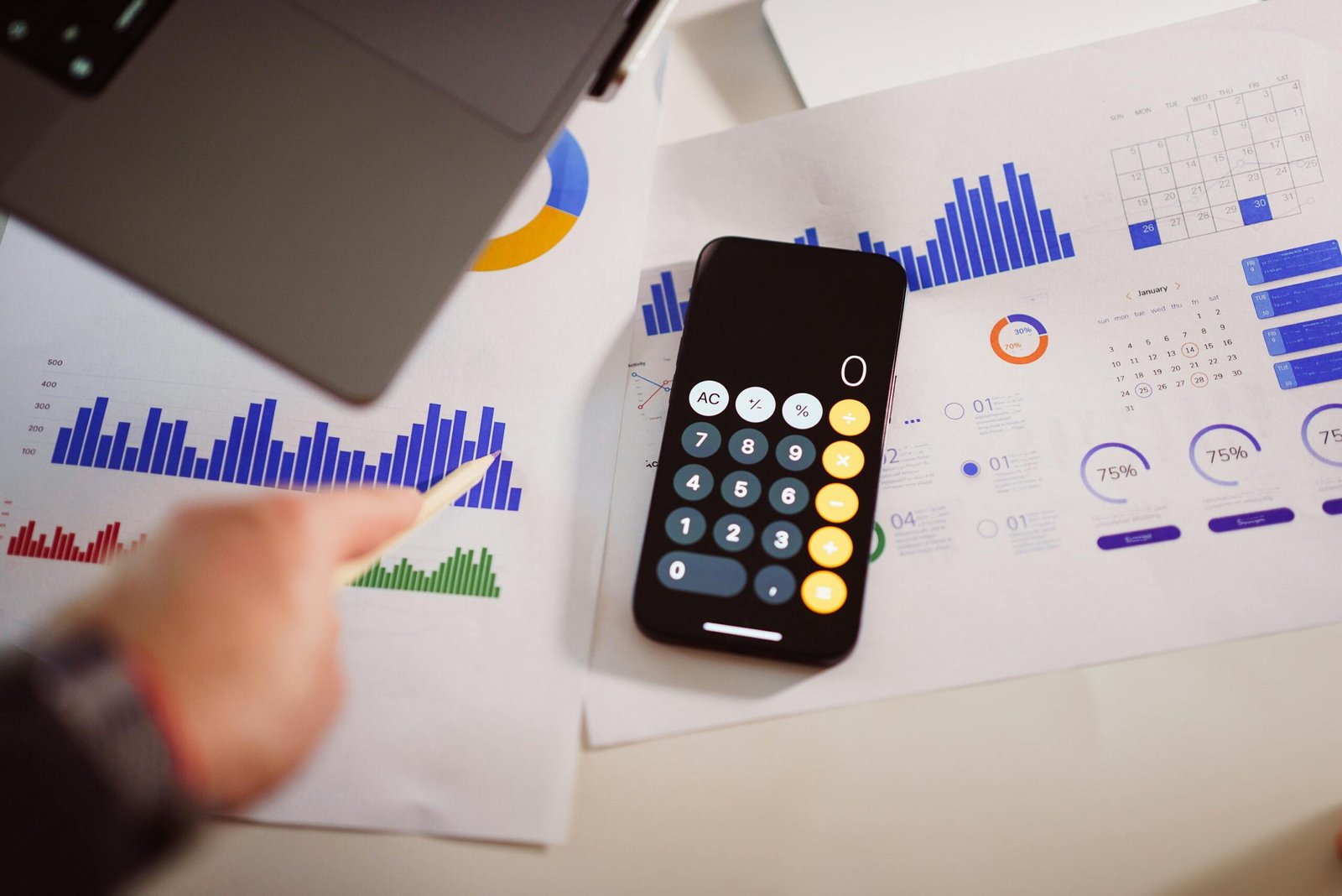 Business analytics setup with calculator, graphs, and laptop, showcasing financial insights.