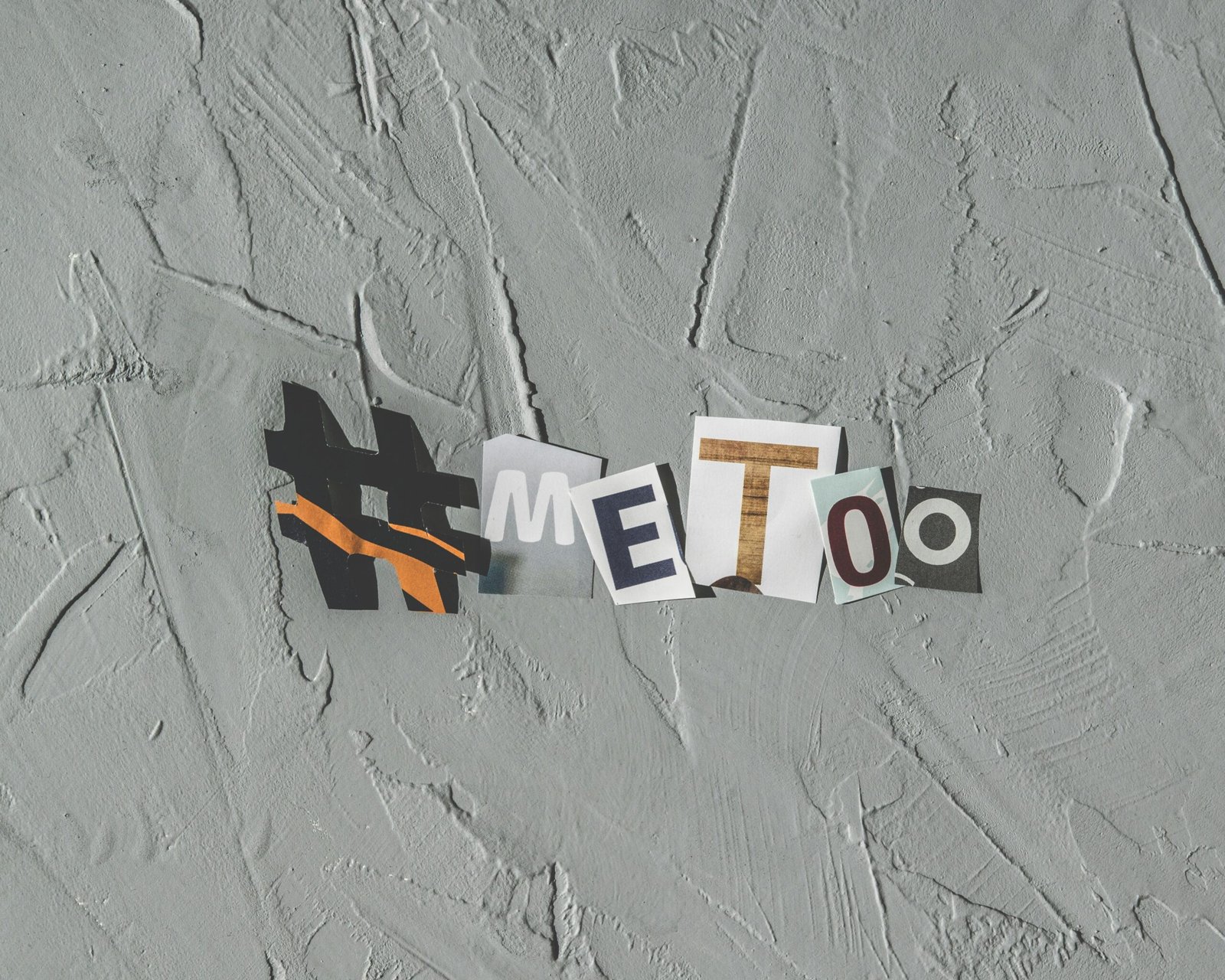 Text art 'MeToo' on concrete background highlighting social movement themes.